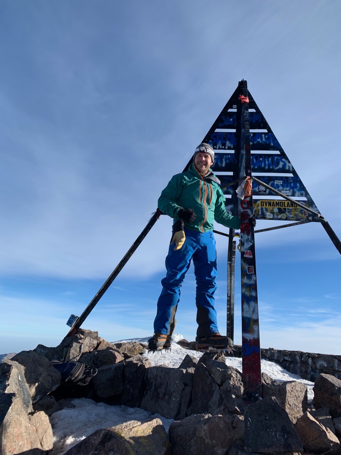 The author standing next to a metal signpost. This is at the top of Mount Toubkal.