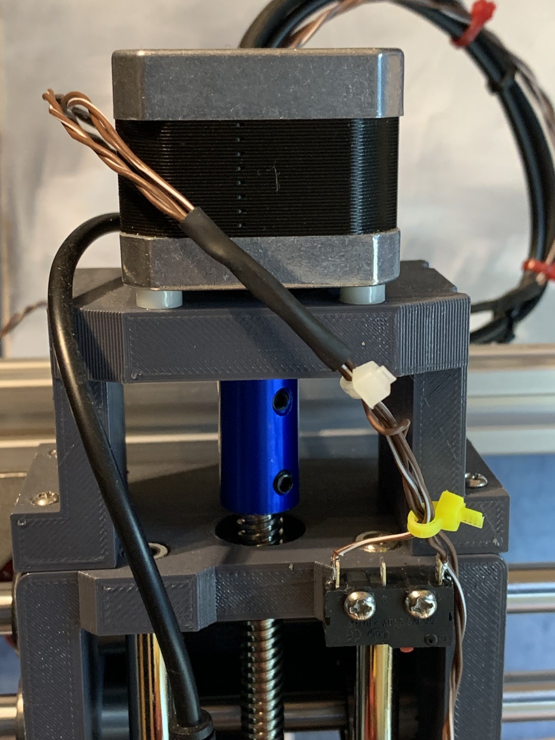 A stepper motor on top of a 3D printed cage. The motor drives a small gantry with a motor inside, which is just out of shot. 