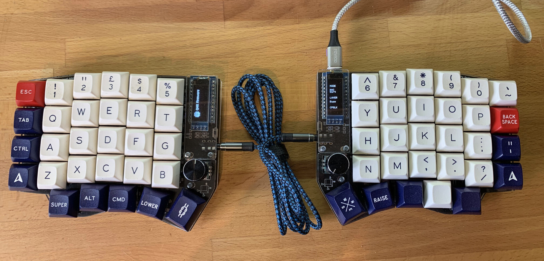 A sofle split keyboard with a braided cable connecting the left and right halves. It’s approximately 60% sized with letters, numbers and the other “important” keys like ctrl, GUI, enter, space etc.