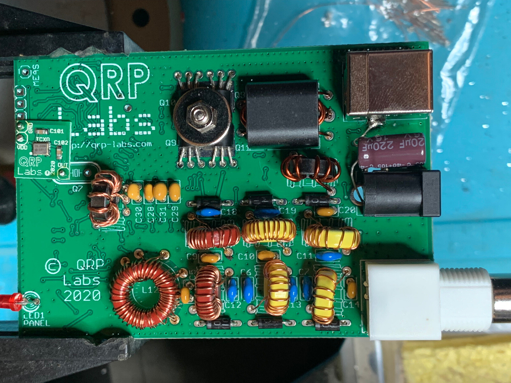 A constructed QDX board with connectors on the right and various components visible, including several inductors. 