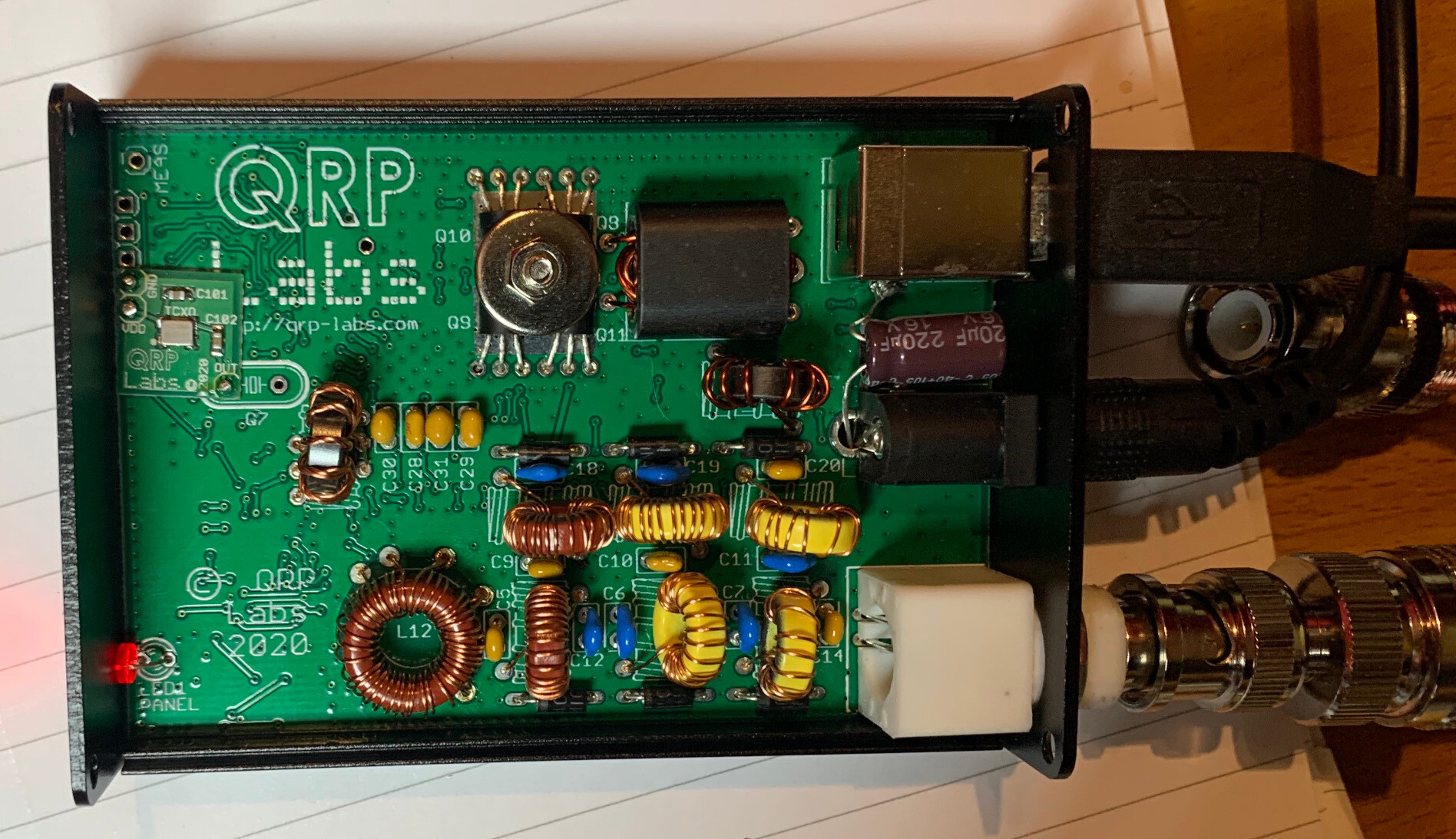 A QDX circuit in an enclosure with the top panel off. There are connectors on the right and several visible components like coils and transistors. 